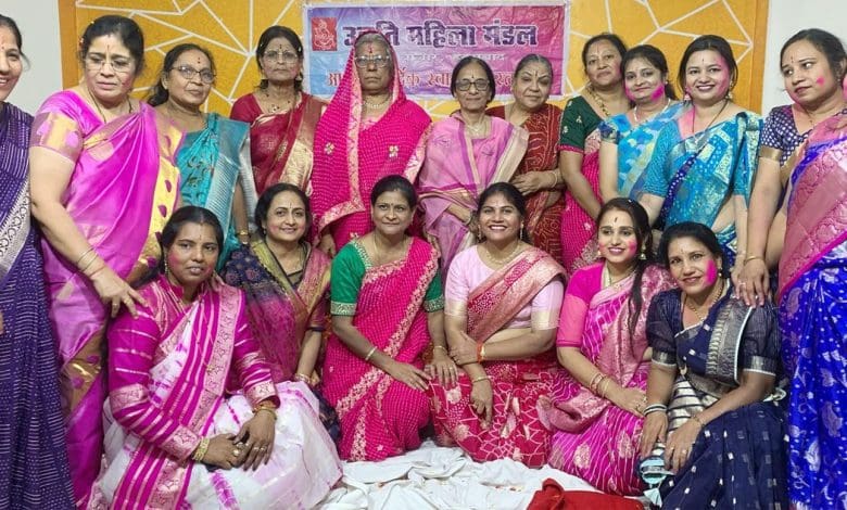 उन्नति महिला मंडल द्वारा आयोजित होली उत्सव में गुलाल और फूलों की होली खेलते हुए लोग।