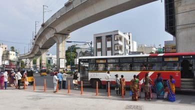 बस स्टैंड पर कड़ी धूप में बस का इंतजार करते लोग