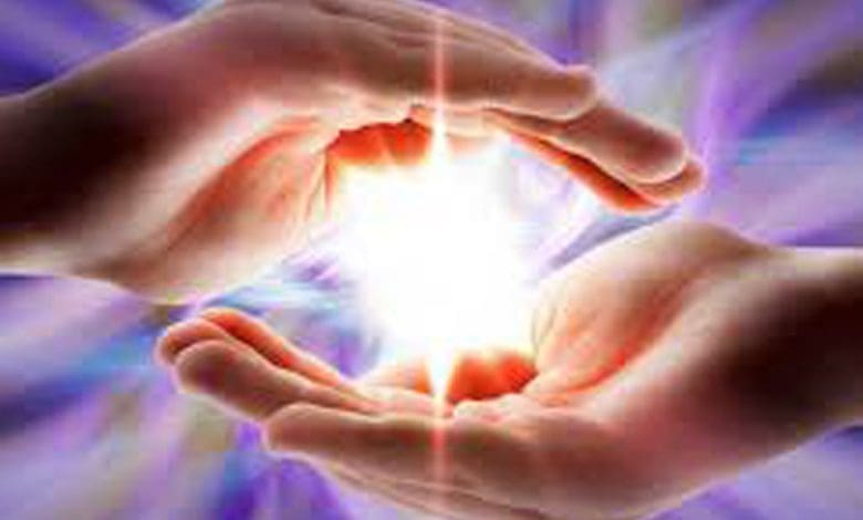 रेकी उपचार करते हुए एक विशेषज्ञ व्यक्ति की हथेलियों से ऊर्जा प्रवाहित करते हुए