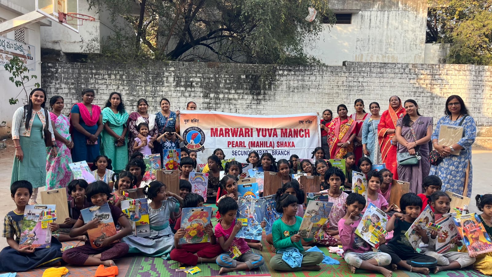 विद्यार्थियों को टी-शर्ट और स्टेशनरी वितरित करते सदस्य